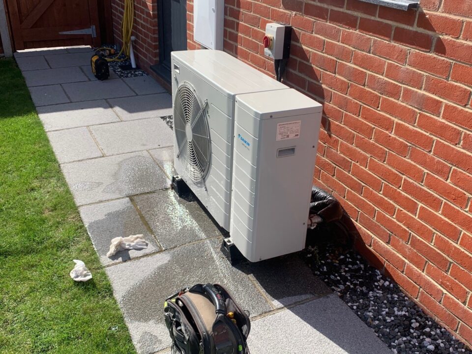Daikin heat pump unit installed outside a building on a paved surface.