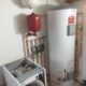 An oil boiler system with a large tank, red expansion vessel, and connected pipes in a utility room.