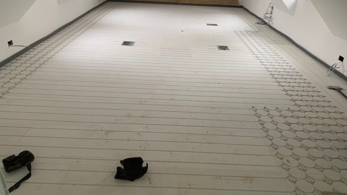 Interior view of a room with partially installed flooring and construction materials visible.