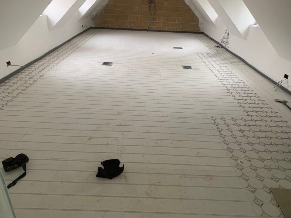 Interior view of a room with partially installed flooring and construction materials visible.